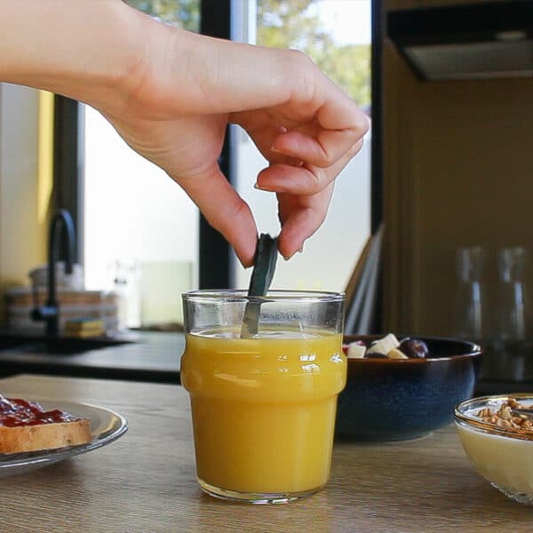 Image d'un verre de jus d'orange frais avec de la spiruline surgelée trempée à l'intérieur, une option nutritive pour booster votre petit déjeuner.