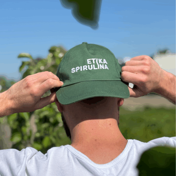 Membre de l’équipe vu de dos portant une casquette Etika Spirulina dans un cadre de production fermière bio