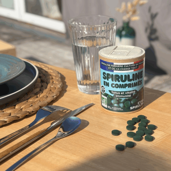 Pot de comprimés de spiruline bio 90g Etika Spirulina posé sur une table à côté d’un repas équilibré