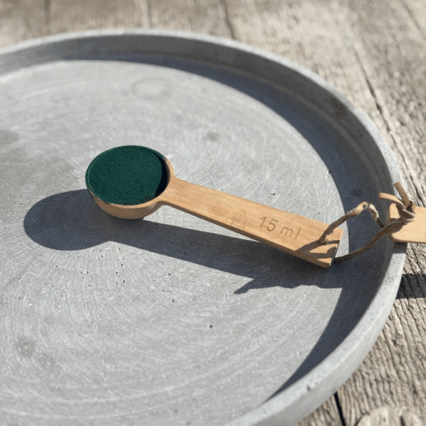 Poudre de spiruline bio dans une cuillère en bois sur fond naturel