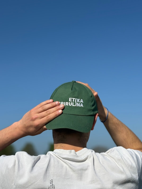 Membre de l’équipe vu de dos portant une casquette Etika Spirulina dans un cadre de production fermière bio